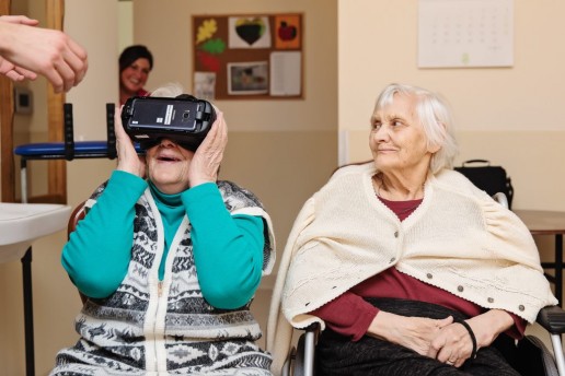 Laimės dienos akimirka - dvi senolės žiūrinčios su virtualios realybės akiniais