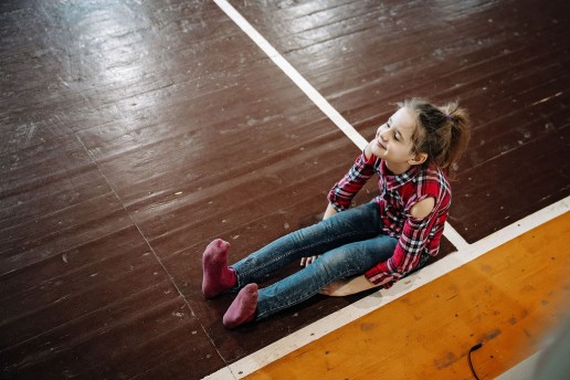 Mergaitė sėdi ant žemės šiuolaikinio cirko dirbtuvių metu